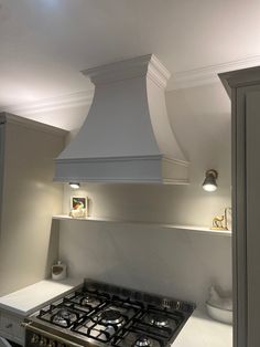 a stove top oven sitting inside of a kitchen next to a wall mounted range hood