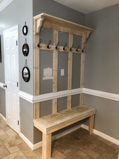 a wooden bench sitting in the middle of a room next to a wall with hooks on it