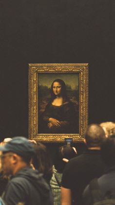 people are looking at a painting on display