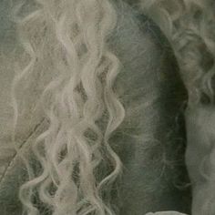 the back of a woman's head with long white hair and curls on it