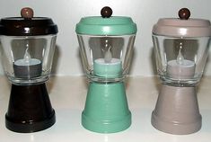 three different colored blenders sitting next to each other on a white counter top with candles in them