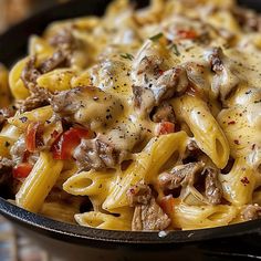 a skillet filled with pasta and meat covered in cheese