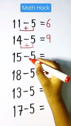 a hand is writing on a white board with numbers