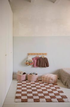 a bedroom with a checkered rug and two small pink stools on the floor