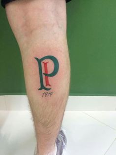 a man's leg with a tattoo on it and the letter p in green