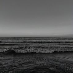 black and white photograph of ocean waves in the foreground, with dark sky above