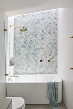 a white bath tub sitting under a window next to a toilet and shower faucet