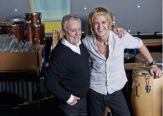 two men standing next to each other in front of musical instruments