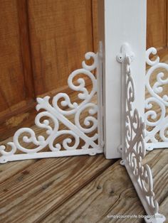 two white iron brackets on the side of a wooden door