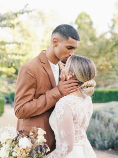 a bride and groom standing next to each other in front of some bushes with flowers