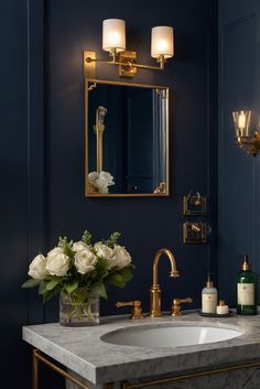 a bathroom with blue walls, gold fixtures and marble countertops is seen in this image