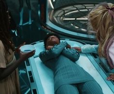 two women are looking at a doll in the back of a space ship while another woman looks on