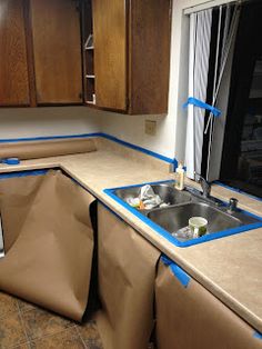 a kitchen that is being remodeled with blue tape on the counter top and sink area