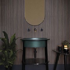 a small table with a mirror on the wall next to a potted plant and two stools