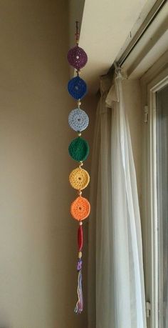 a multicolored wind chime hanging from the side of a window sill