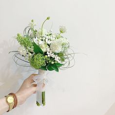 a person holding a bouquet of white flowers in their left hand and wearing a watch