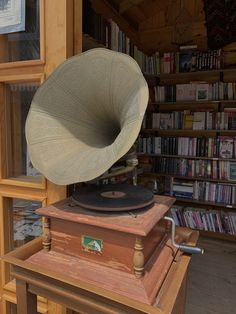 an old record player sitting on top of a wooden stand in front of a bookshelf