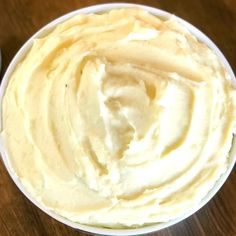 a cup filled with whipped cream sitting on top of a wooden table