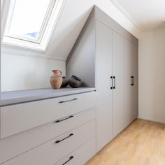 an attic bedroom with white cabinets and drawers