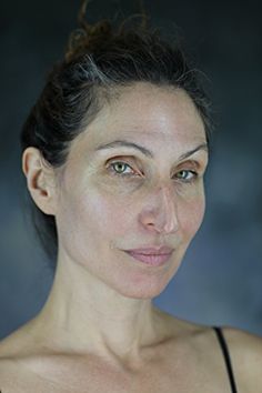 a woman is posing for the camera with her eyes wide open, wearing a black tank top