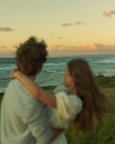 a man and woman standing next to each other near the ocean