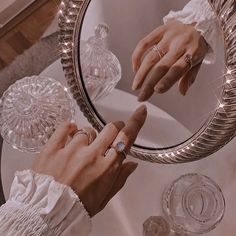 two hands touching each other's fingers in front of a round mirror on a table