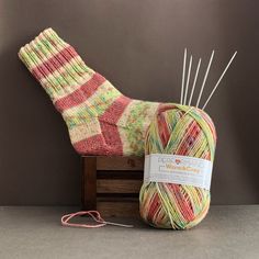 a skein of yarn sitting on top of a wooden box next to a ball of knitting needles