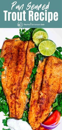 two fish fillets with greens and limes on a white plate, ready to be eaten