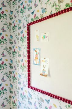 a white wall with colorful butterflies on it and red trim around the edges, along with small magnets