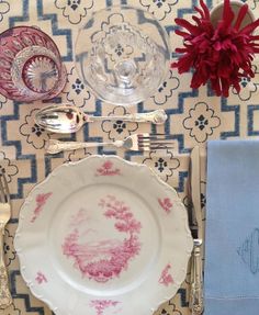 a place setting with silverware and pink flowers on a tableclothed table cloth