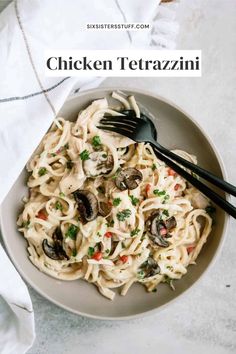 a white bowl filled with chicken tetrazzini next to a fork and napkin