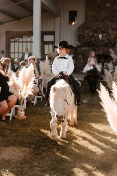 a young boy riding on the back of a white horse in front of an audience