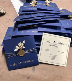 blue wedding cards with white flowers and gold accents are on the floor next to each other