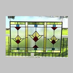 a large stained glass window sitting on top of a metal fence in front of a green field