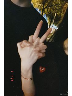 a person making the peace sign with their hand and holding a red heart in front of them