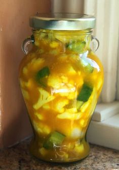 a glass jar filled with pickles and cucumbers on top of a counter