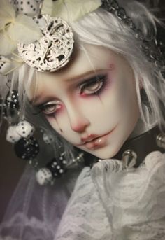 a close up of a doll with white hair and black eye make - up on her face