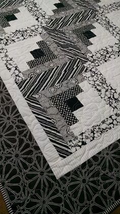 a black and white quilt is laying on top of a tablecloth with an intricate design