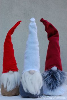 three gnomes with red and white hats on their heads, one is upside down