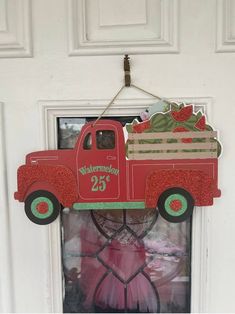 a red truck hanging from the side of a door with a christmas decoration on it