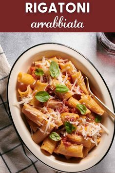 a white bowl filled with pasta and topped with parmesan cheese, basil leaves