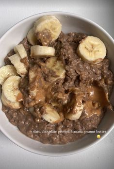 a white bowl filled with oatmeal and bananas on top of a table