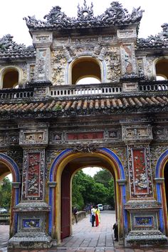 people walking under an ornate archway in the city