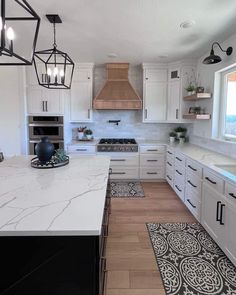 a large kitchen with white cabinets and marble counter tops, an island in the middle