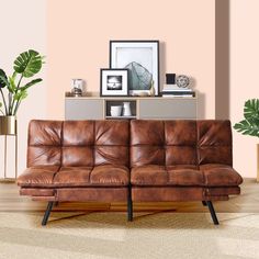 a brown leather couch sitting on top of a wooden floor next to a potted plant