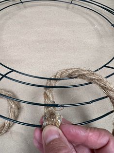 someone is making a wire wreath with twine