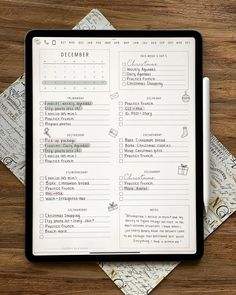 a black and white planner sitting on top of a wooden table next to some papers