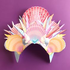 a paper mask with shells and seashells on it's face against a purple background