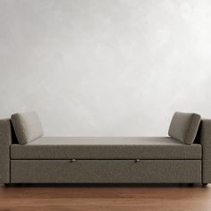 a couch sitting on top of a hard wood floor next to a white wall in an empty room