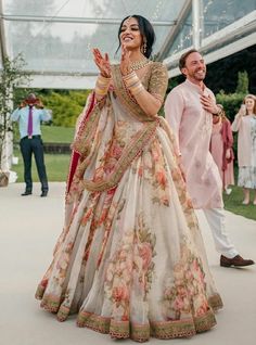 two people standing next to each other in wedding outfits holding hands and looking at each other